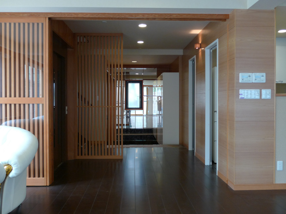 На фото: узкая прихожая среднего размера в стиле фьюжн с коричневыми стенами, полом из фанеры, раздвижной входной дверью, входной дверью из светлого дерева, коричневым полом, потолком с обоями и деревянными стенами