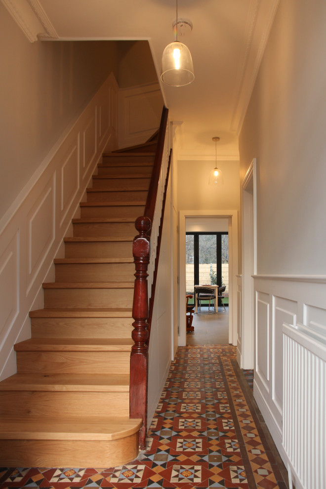 Photo of a small contemporary hallway in London with white walls, terra-cotta floors and multi-coloured floor.