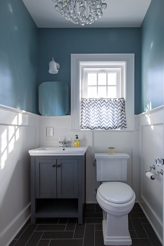 Mid-sized transitional powder room in New York with grey cabinets, a two-piece toilet, black tile, blue walls, porcelain floors and a drop-in sink.