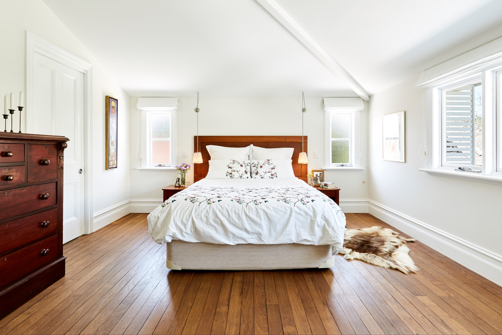 This is an example of a large traditional master bedroom in Sydney with white walls, medium hardwood floors and brown floor.