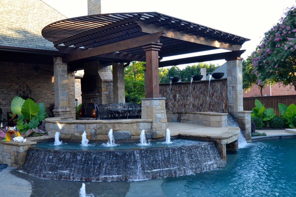 Photo of a large transitional backyard custom-shaped pool in Dallas with stamped concrete and a water feature.