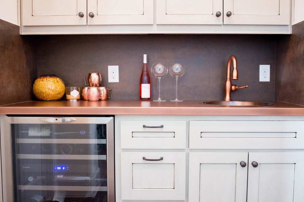 Photo of a mid-sized transitional single-wall seated home bar in Austin with white cabinets, copper benchtops, multi-coloured splashback, an undermount sink and shaker cabinets.
