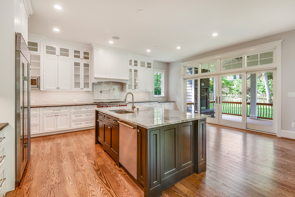 Example of a large transitional l-shaped medium tone wood floor and brown floor open concept kitchen design in DC Metro with an undermount sink, recessed-panel cabinets, white cabinets, quartzite countertops, white backsplash, subway tile backsplash, stainless steel appliances, an island and white countertops