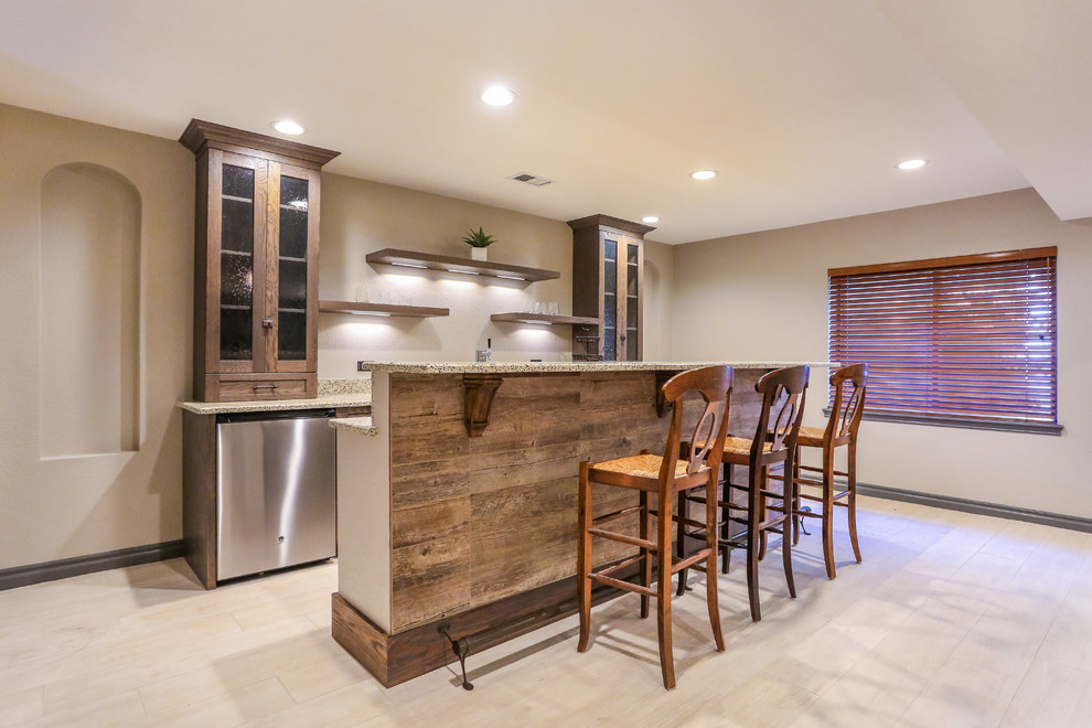 This is an example of a mid-sized country galley home bar in Denver with glass-front cabinets, dark wood cabinets, granite benchtops, porcelain floors and beige floor.