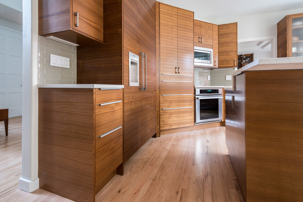 Mid-sized minimalist u-shaped light wood floor eat-in kitchen photo in Seattle with an undermount sink, flat-panel cabinets, medium tone wood cabinets, quartz countertops, green backsplash, glass tile backsplash, paneled appliances and an island