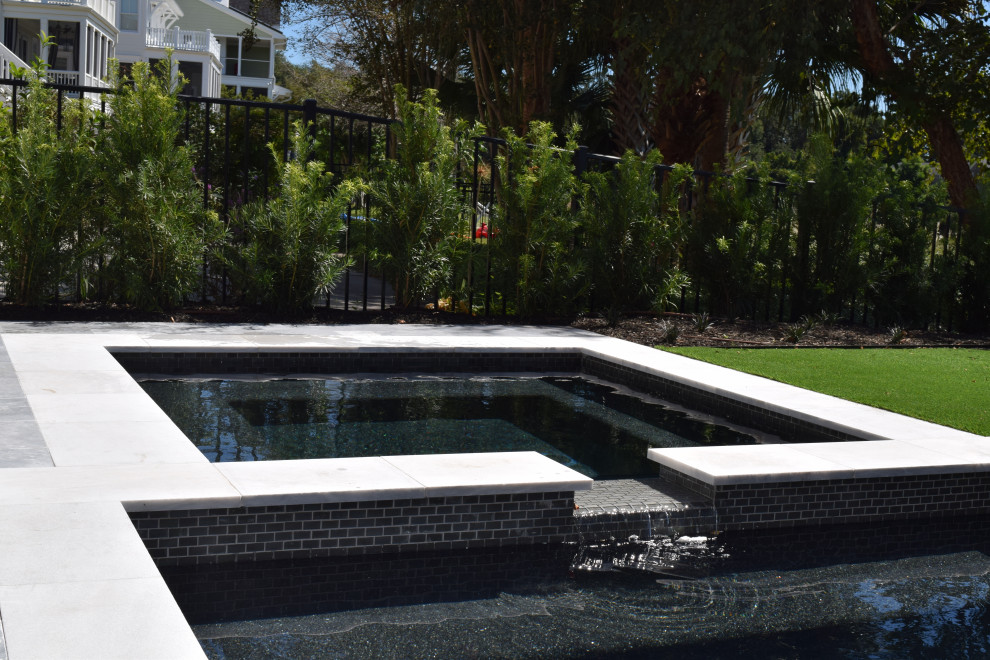 Modelo de piscina actual pequeña en patio trasero con adoquines de piedra natural