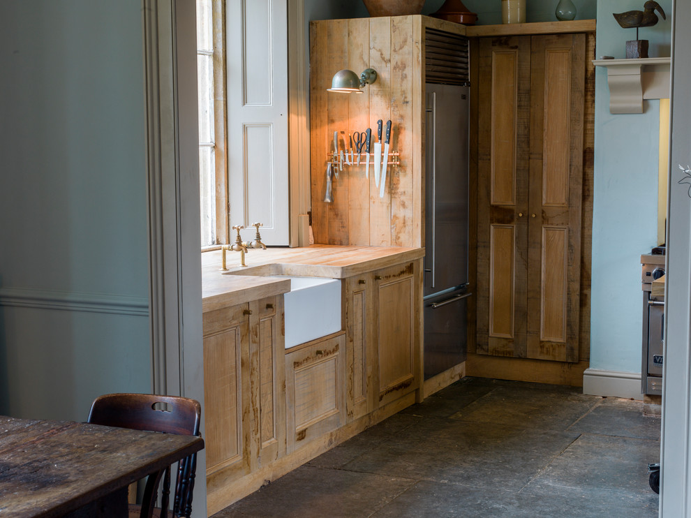 Design ideas for a large rustic u-shaped kitchen/diner in Wiltshire with a belfast sink, shaker cabinets, distressed cabinets, wood worktops, stainless steel appliances, slate flooring and an island.