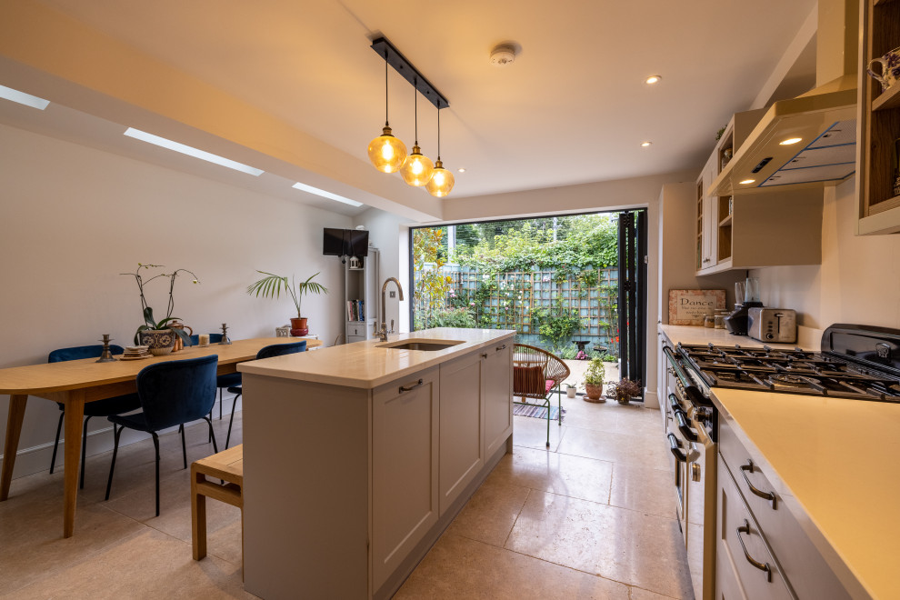 Mid-sized modern eat-in kitchen in London with grey cabinets, with island, beige floor and white benchtop.