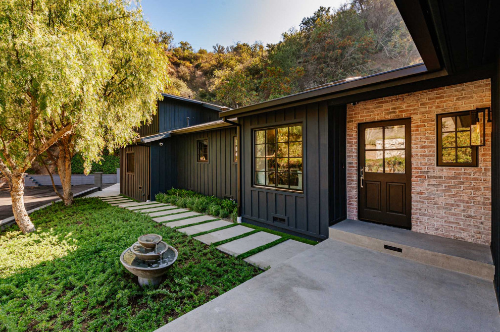 This is an example of a large country split-level black house exterior in Los Angeles with wood siding.