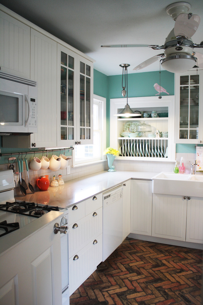 This is an example of a traditional kitchen in Austin with a farmhouse sink, flat-panel cabinets, white cabinets, white splashback, subway tile splashback and white appliances.