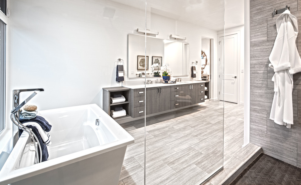 This is an example of a large transitional master bathroom in Seattle with flat-panel cabinets, medium wood cabinets, a freestanding tub, an open shower, a two-piece toilet, white tile, porcelain tile, white walls, porcelain floors, an undermount sink, engineered quartz benchtops, grey floor, an open shower and white benchtops.