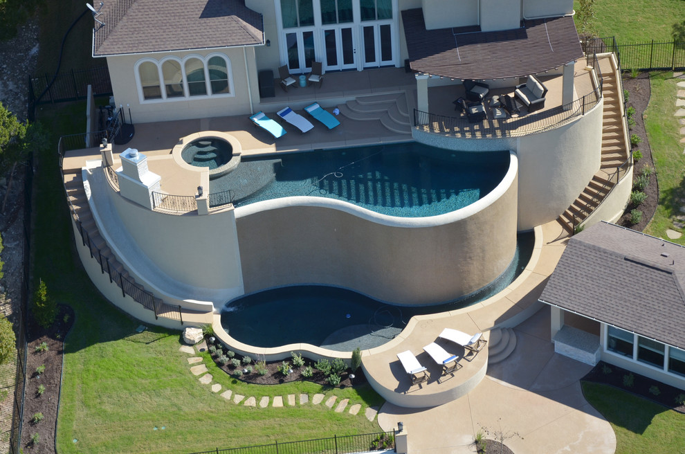 Inspiration for a large modern custom-shaped infinity pool in Austin with stamped concrete.
