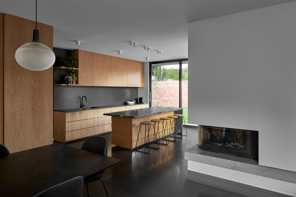 Photo of a contemporary kitchen in Melbourne with marble benchtops, black splashback, stone slab splashback, concrete floors and black benchtop.