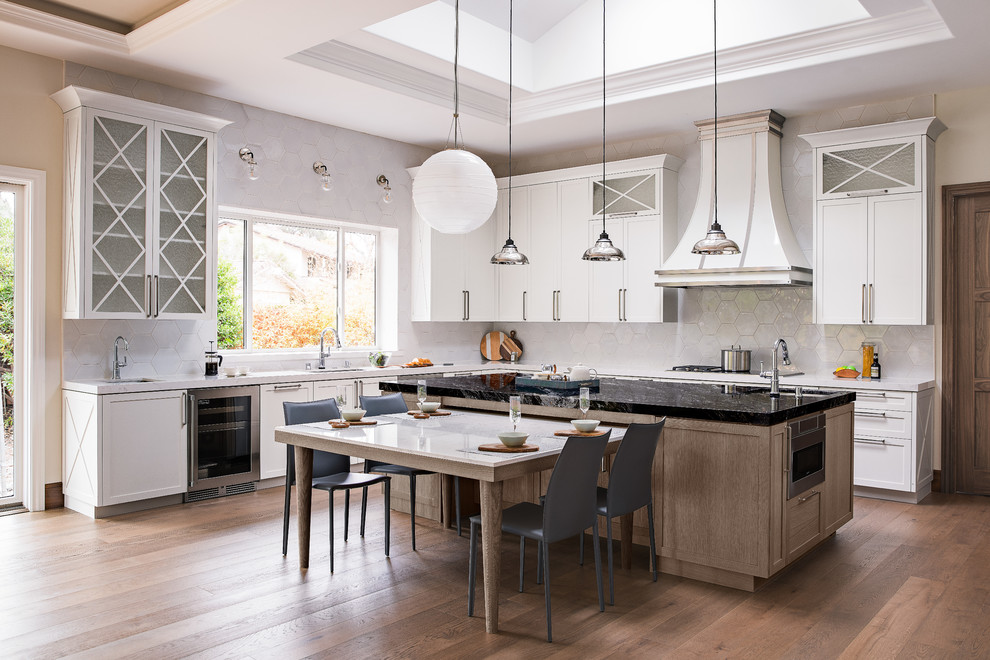Design ideas for a large transitional u-shaped open plan kitchen in Atlanta with a double-bowl sink, shaker cabinets, light wood cabinets, quartz benchtops, white splashback, ceramic splashback, stainless steel appliances, medium hardwood floors, with island and white benchtop.
