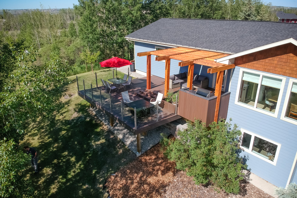 Example of a mid-sized trendy backyard deck design in Calgary with a pergola
