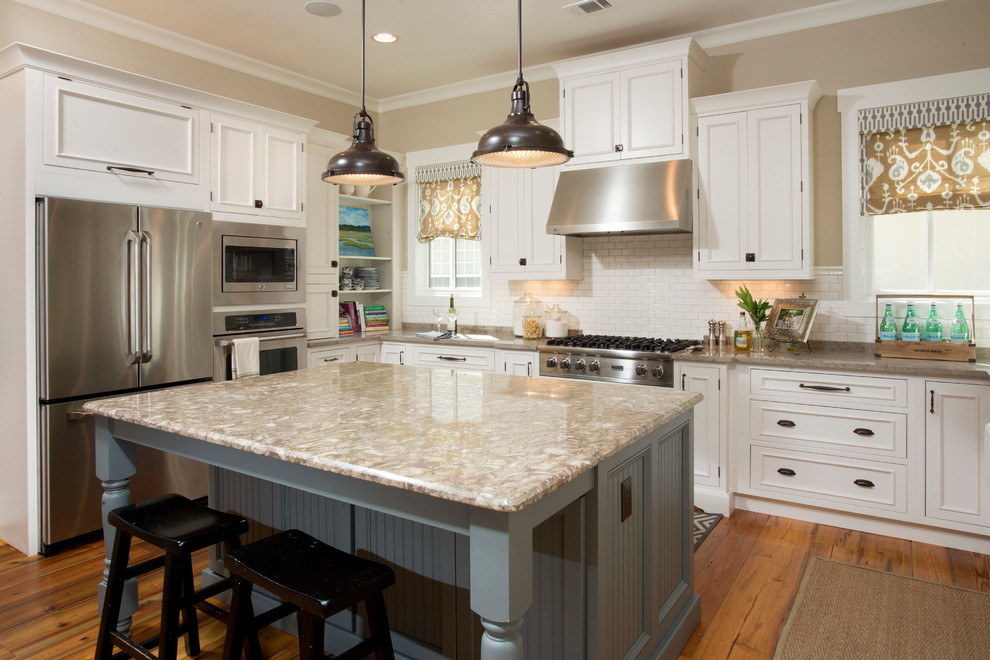 This is an example of a mid-sized country u-shaped kitchen in Charleston with white cabinets, white splashback, subway tile splashback, stainless steel appliances, medium hardwood floors, with island and raised-panel cabinets.