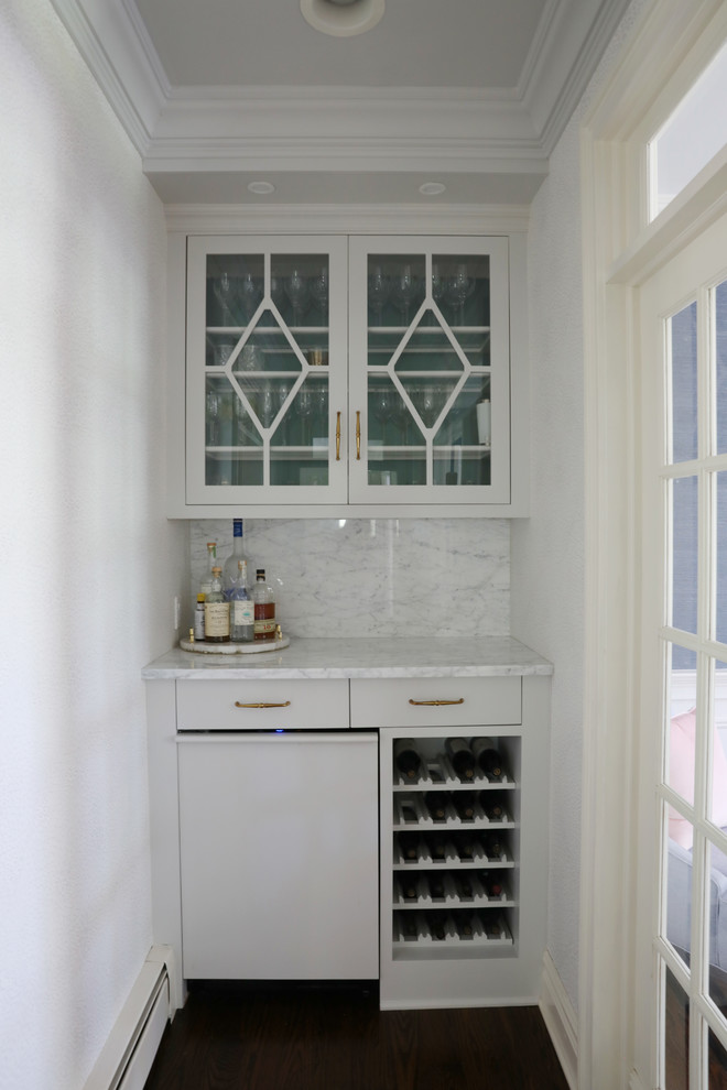 This is an example of a small transitional single-wall home bar in New York with no sink, glass-front cabinets, grey cabinets, marble benchtops, grey splashback, marble splashback, dark hardwood floors, brown floor and grey benchtop.