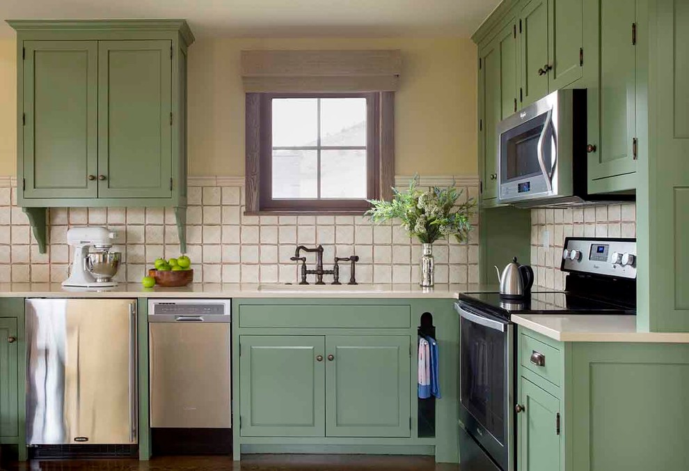 Inspiration for a traditional l-shaped kitchen in Los Angeles with an undermount sink, shaker cabinets, green cabinets, quartz benchtops, beige splashback, ceramic splashback and stainless steel appliances.