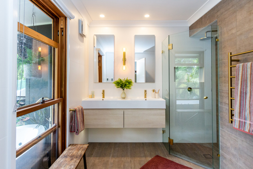 Inspiration for a mid-sized mediterranean 3/4 bathroom in Sydney with flat-panel cabinets, light wood cabinets, a freestanding tub, a corner shower, a two-piece toilet, an integrated sink, a hinged shower door, a niche, a double vanity, a floating vanity and white benchtops.