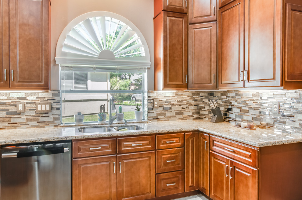 Large traditional l-shaped eat-in kitchen in Houston with a double-bowl sink, raised-panel cabinets, brown cabinets, granite benchtops, brown splashback, glass sheet splashback, black appliances, marble floors, with island, brown floor and brown benchtop.