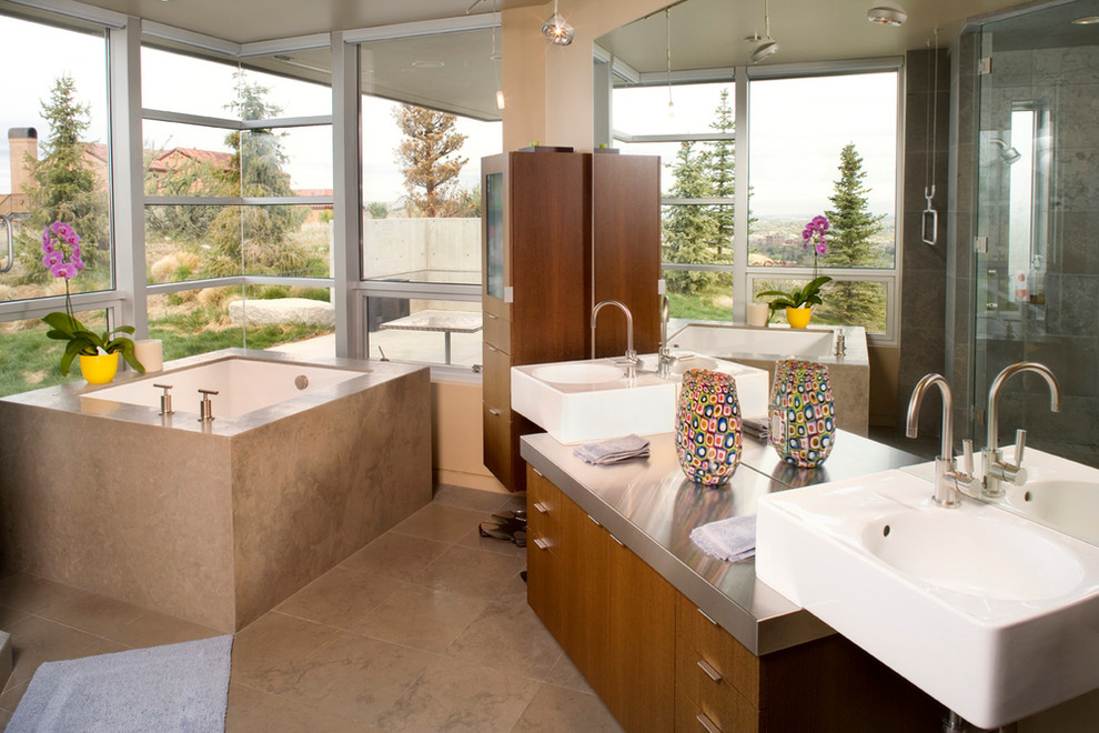 Large modern master bathroom in Boise with flat-panel cabinets, medium wood cabinets, a drop-in tub, a corner shower, beige tile, ceramic tile, beige walls, ceramic floors, a pedestal sink and stainless steel benchtops.