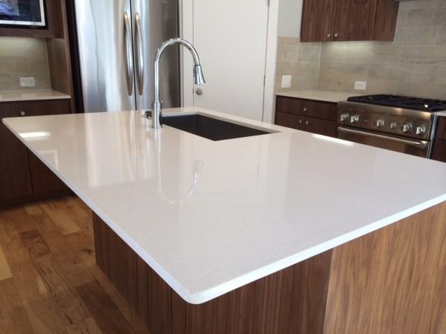 Kitchen - mid-sized transitional u-shaped medium tone wood floor and brown floor kitchen idea in Austin with an undermount sink, flat-panel cabinets, brown cabinets, stainless steel appliances, an island, quartz countertops, gray backsplash and white countertops