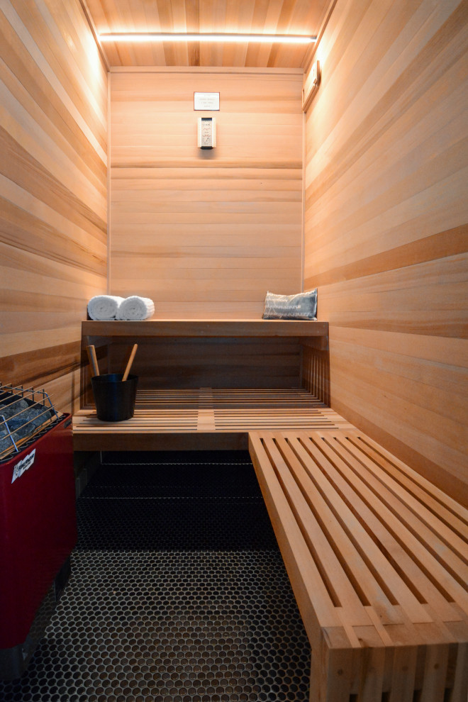 Große Moderne Sauna mit brauner Wandfarbe, Keramikboden, schwarzem Boden, Falttür-Duschabtrennung, Duschbank, Holzdecke und Holzwänden in Sonstige