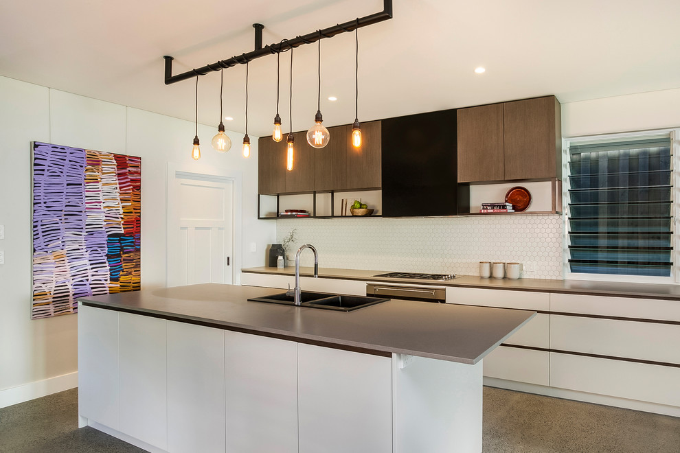 Inspiration for a mid-sized contemporary galley kitchen in Sydney with white splashback, with island, a drop-in sink, flat-panel cabinets, white cabinets, grey floor and grey benchtop.