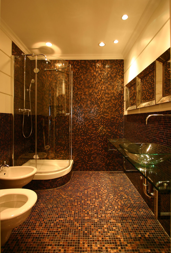 This is an example of a mid-sized contemporary master bathroom in Rome with a wall-mount sink, open cabinets, glass benchtops, a corner shower, a wall-mount toilet, gray tile, mosaic tile, brown walls and mosaic tile floors.