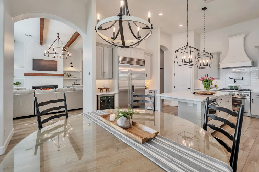 Large transitional u-shaped porcelain tile, brown floor and exposed beam kitchen photo in Phoenix with a farmhouse sink, shaker cabinets, gray cabinets, quartzite countertops, white backsplash, porcelain backsplash, stainless steel appliances, an island and white countertops