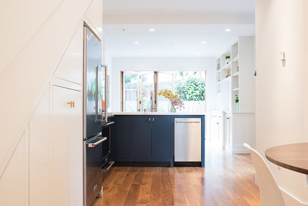Small scandinavian l-shaped open plan kitchen in San Francisco with an undermount sink, flat-panel cabinets, blue cabinets, quartzite benchtops, white splashback, stone slab splashback, stainless steel appliances, light hardwood floors and no island.