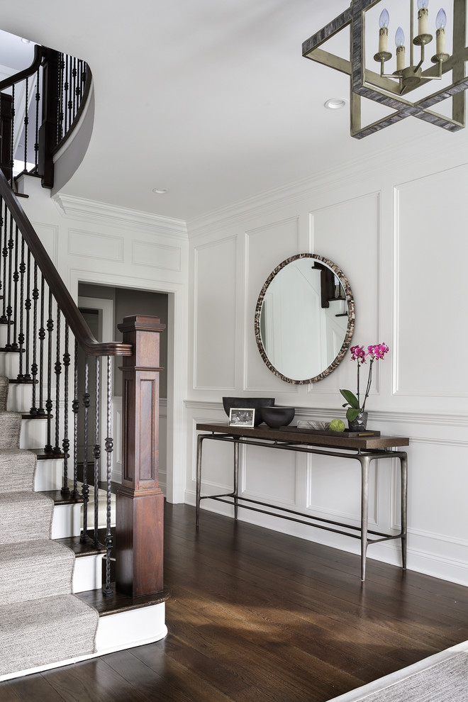 This is an example of a mid-sized transitional foyer in New York with white walls, dark hardwood floors, a single front door and brown floor.
