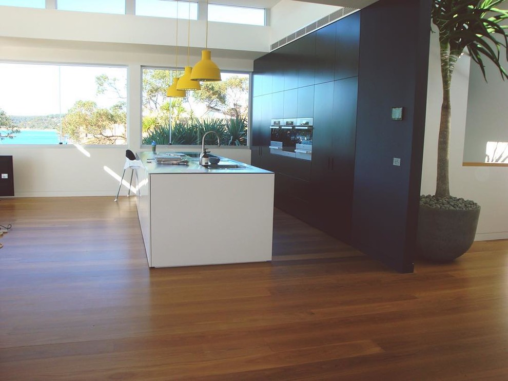 Photo of a large contemporary open plan kitchen in Sydney with flat-panel cabinets, black cabinets, glass benchtops and with island.
