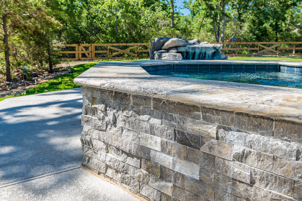Photo of a large traditional backyard custom-shaped natural pool in Other with a hot tub and concrete slab.