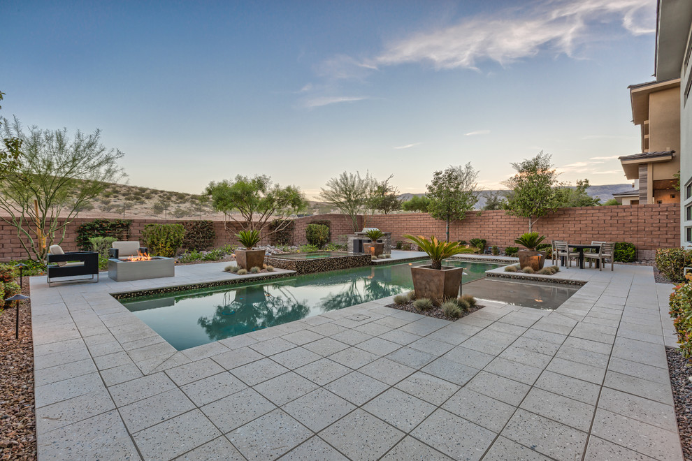 Inspiration for a large tropical backyard rectangular lap pool in Las Vegas with a hot tub and natural stone pavers.