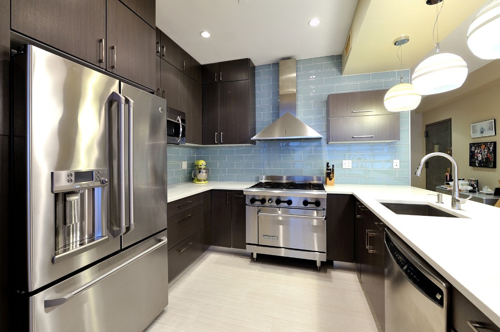 This is an example of a contemporary u-shaped eat-in kitchen in New York with an undermount sink, flat-panel cabinets, dark wood cabinets, wood benchtops, blue splashback, ceramic splashback and stainless steel appliances.