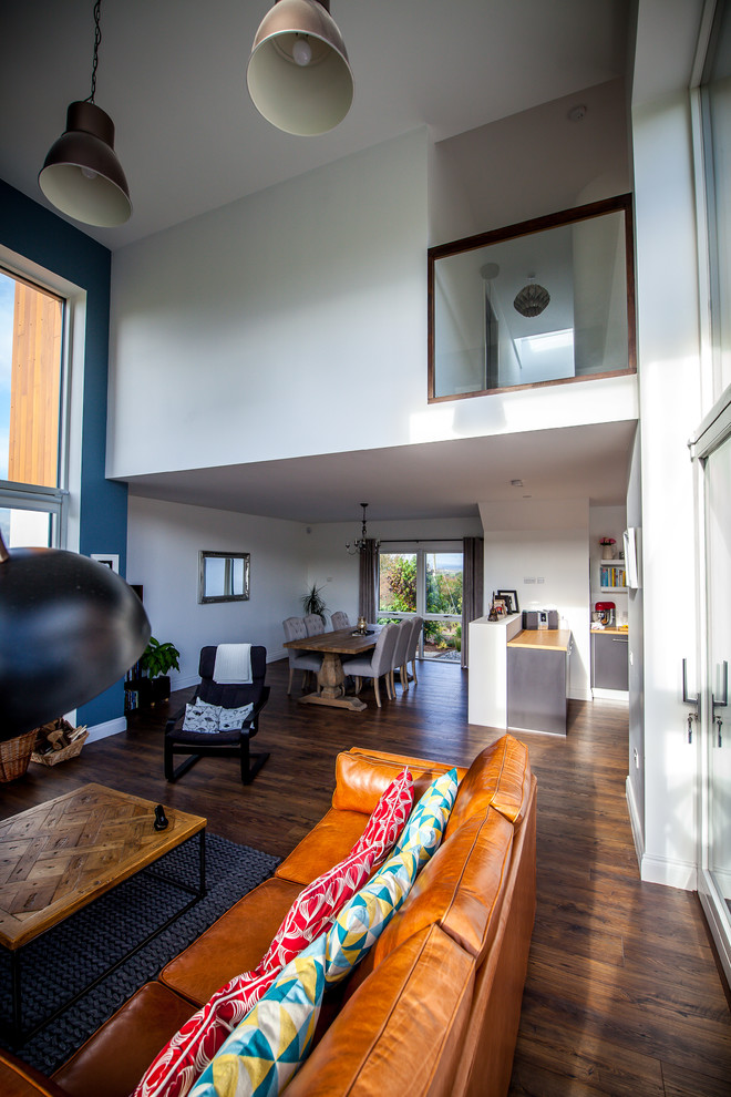 This is an example of a mid-sized contemporary open concept living room in Cork with multi-coloured walls, dark hardwood floors, no fireplace and no tv.