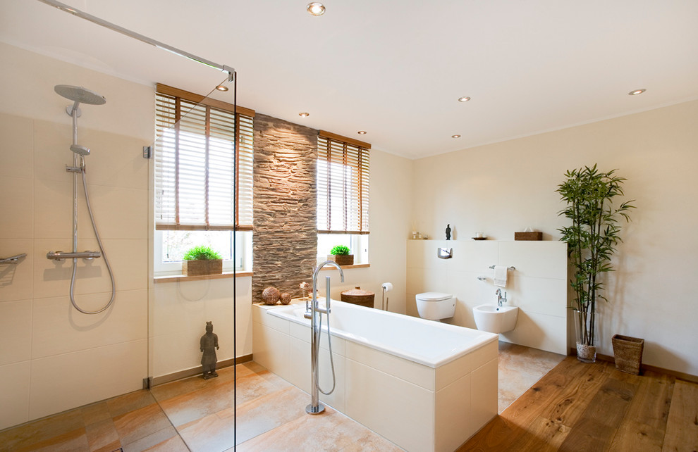 Mid-sized asian master bathroom in Frankfurt with flat-panel cabinets, medium wood cabinets, a freestanding tub, a curbless shower, stone tile, beige walls, medium hardwood floors, a vessel sink, a bidet, beige tile and an open shower.