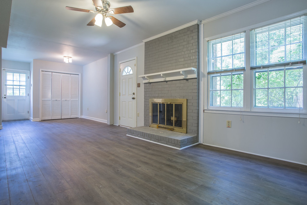 This is an example of a mid-sized transitional formal enclosed living room in Charlotte with beige walls, a standard fireplace, a brick fireplace surround and grey floor.
