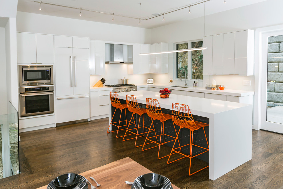 This is an example of a mid-sized modern l-shaped eat-in kitchen in Cincinnati with an undermount sink, flat-panel cabinets, white cabinets, quartz benchtops, stainless steel appliances, dark hardwood floors, with island, brown floor and white benchtop.