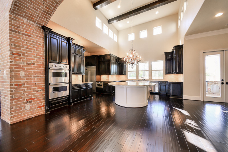 Open concept kitchen - large transitional u-shaped dark wood floor open concept kitchen idea in Houston with a farmhouse sink, dark wood cabinets, granite countertops, beige backsplash, ceramic backsplash, stainless steel appliances and an island