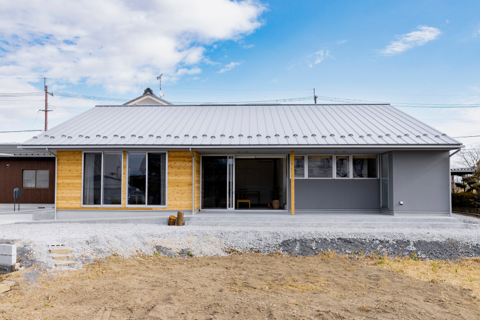 This is an example of a mid-sized scandinavian one-storey concrete grey house exterior in Other with a hip roof, a metal roof, a grey roof and shingle siding.