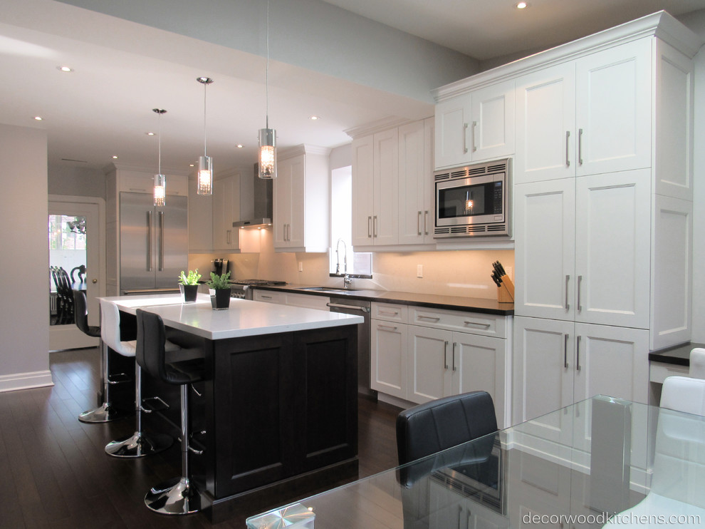 Enclosed kitchen - large transitional l-shaped dark wood floor enclosed kitchen idea in Toronto with an undermount sink, shaker cabinets, white cabinets, quartz countertops, white backsplash, stone slab backsplash, stainless steel appliances and an island