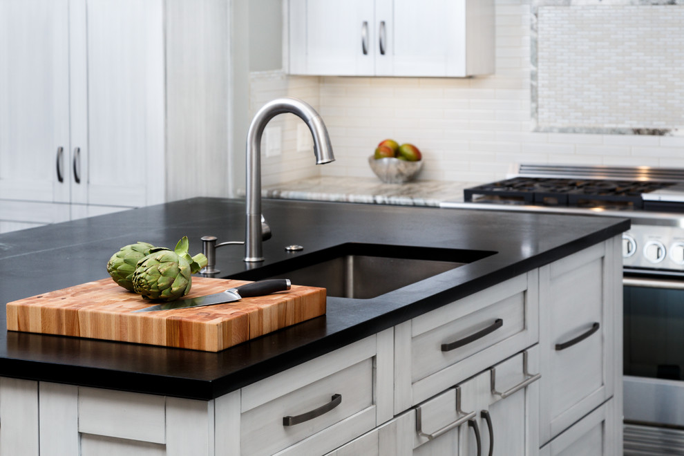 Inspiration for a large transitional l-shaped porcelain tile eat-in kitchen remodel in Austin with a single-bowl sink, shaker cabinets, gray cabinets, soapstone countertops, white backsplash, ceramic backsplash, stainless steel appliances and an island