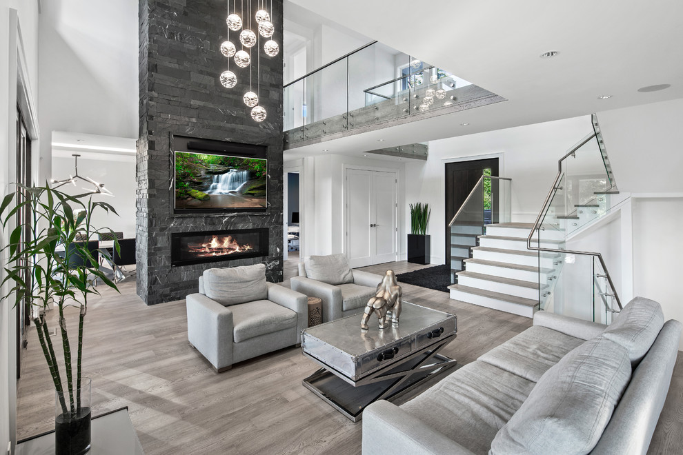 Inspiration for a contemporary open concept family room in Vancouver with white walls, light hardwood floors, a ribbon fireplace, a stone fireplace surround and a wall-mounted tv.