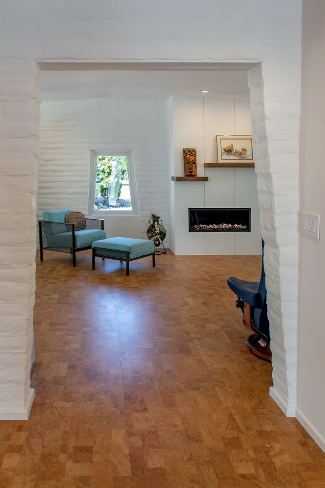 На фото: изолированная гостиная комната среднего размера в стиле ретро с белыми стенами, пробковым полом, горизонтальным камином, сводчатым потолком и акцентной стеной