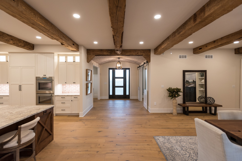 Geräumiger Landhaus Eingang mit braunem Holzboden, braunem Boden und freigelegten Dachbalken in Sonstige