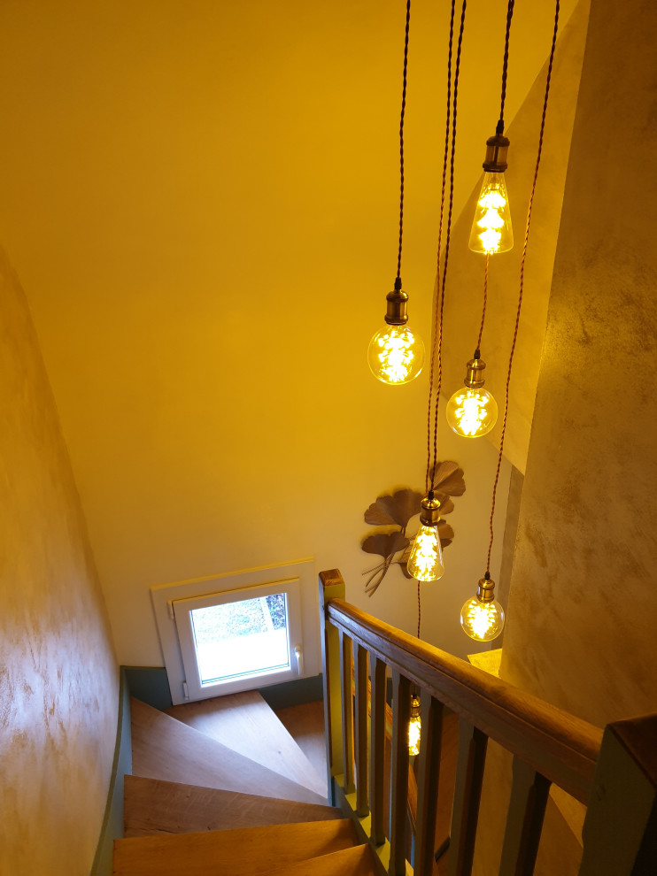 Пример оригинального дизайна: узкая прихожая среднего размера: освещение в стиле неоклассика (современная классика) с бежевыми стенами, светлым паркетным полом, одностворчатой входной дверью, входной дверью из дерева среднего тона, коричневым полом и обоями на стенах
