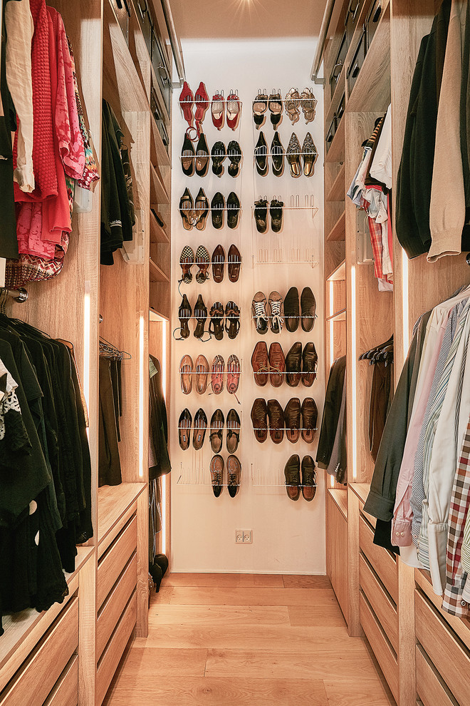 This is an example of a contemporary walk-in wardrobe in Copenhagen with flat-panel cabinets, light wood cabinets, light hardwood floors and beige floor.