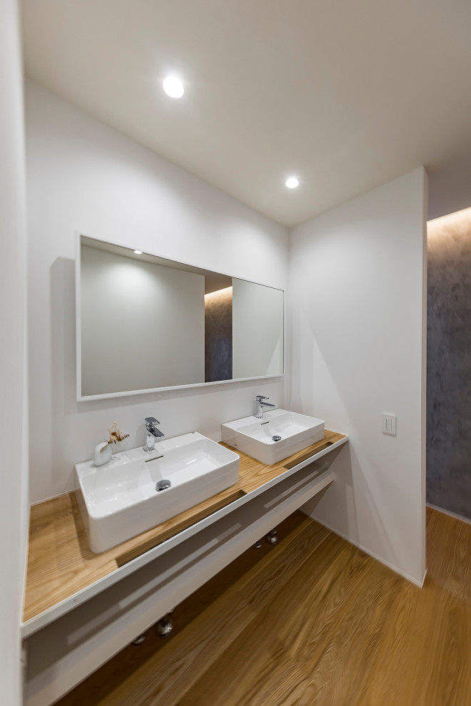 Design ideas for a modern powder room in Other with open cabinets, white walls, medium hardwood floors, a vessel sink, wood benchtops, brown floor, brown benchtops, a built-in vanity and wallpaper.